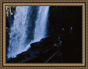 Walking The Plank Framed Paintings - Hikers Walking Behind Scenic Dry Falls at The Base by Raymond Gehman